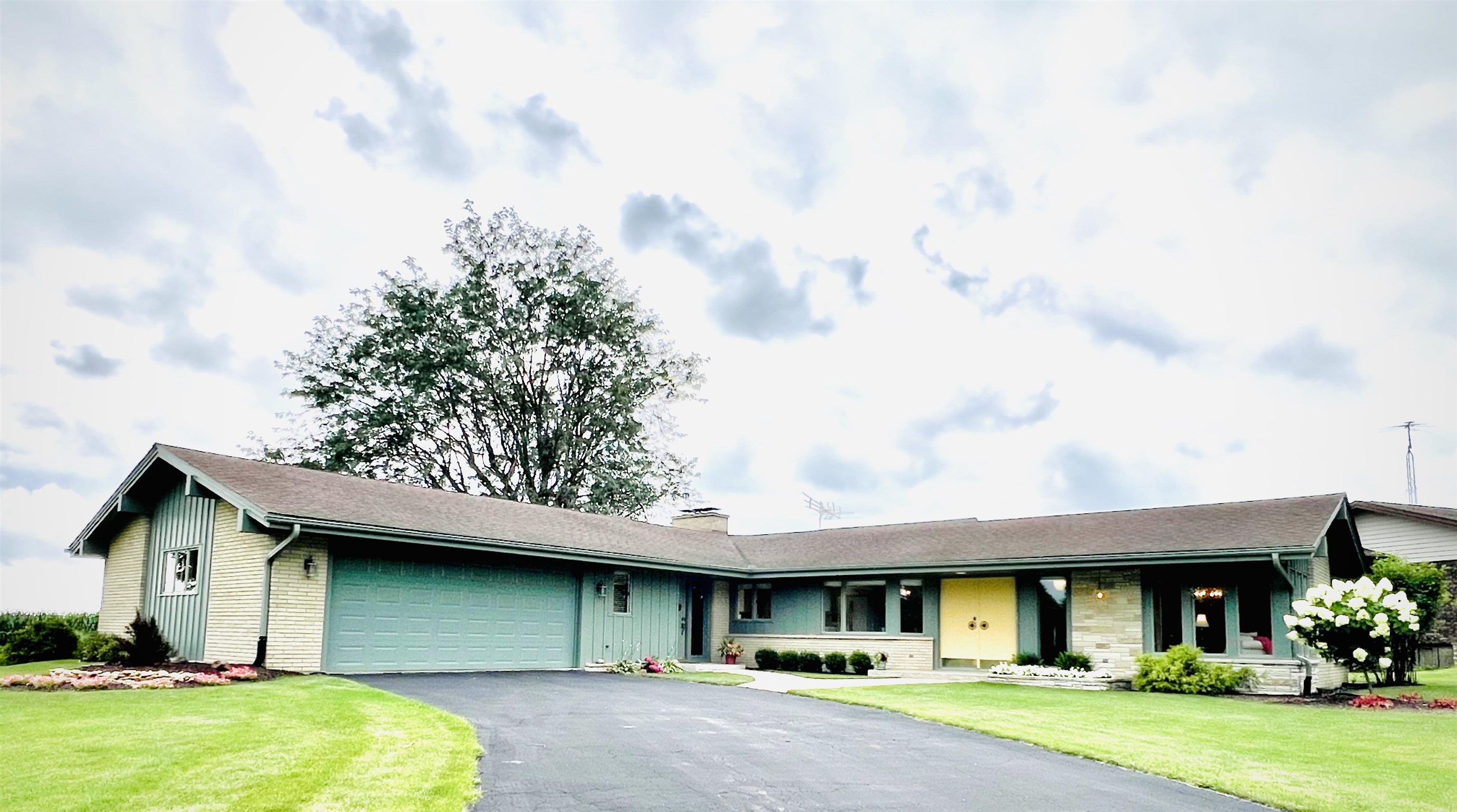 a view of a brick house with a yard and large trees