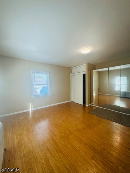 an empty room with wooden floor and mirror