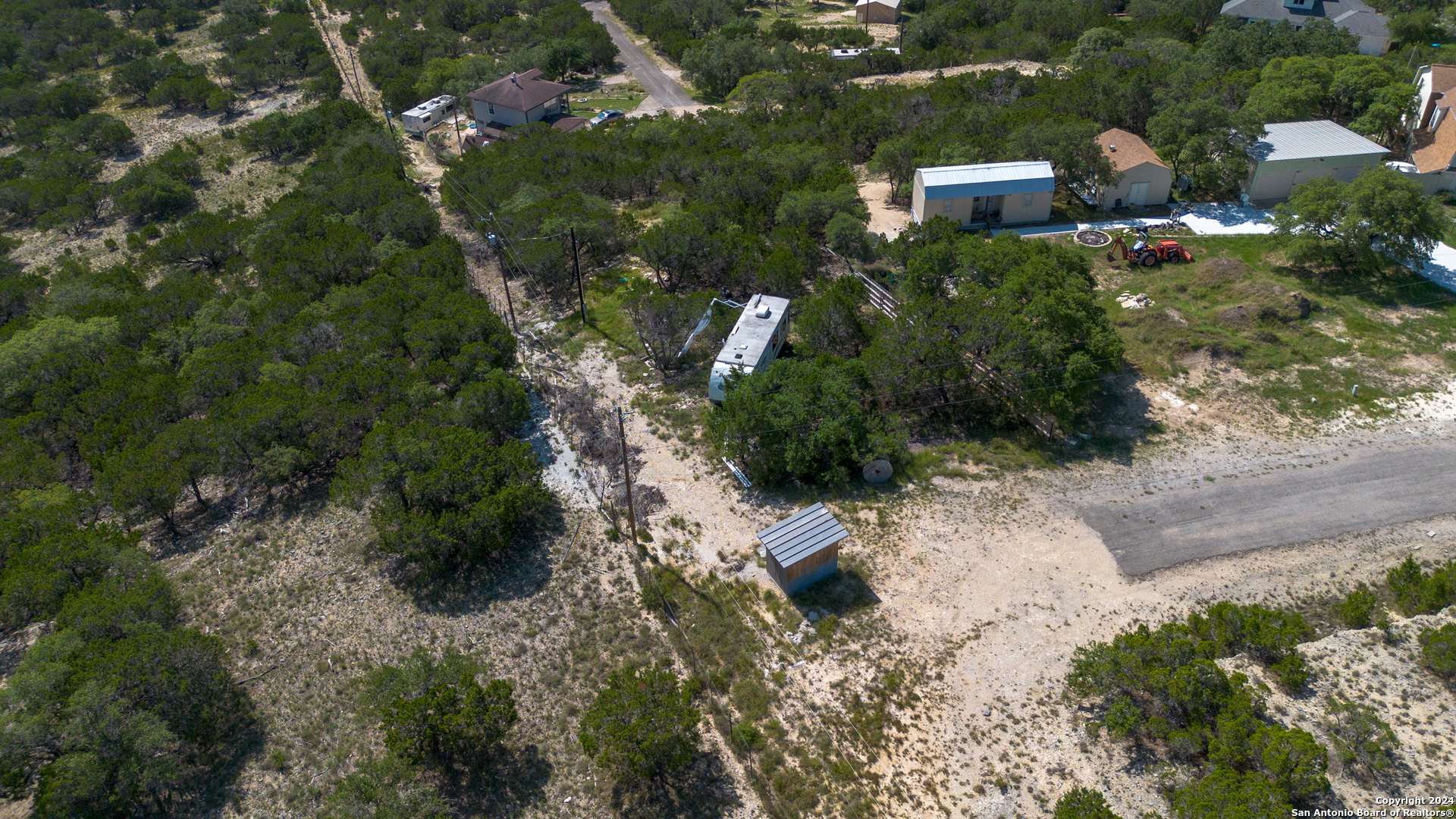 an aerial view of residential house with outdoor space and trees all around