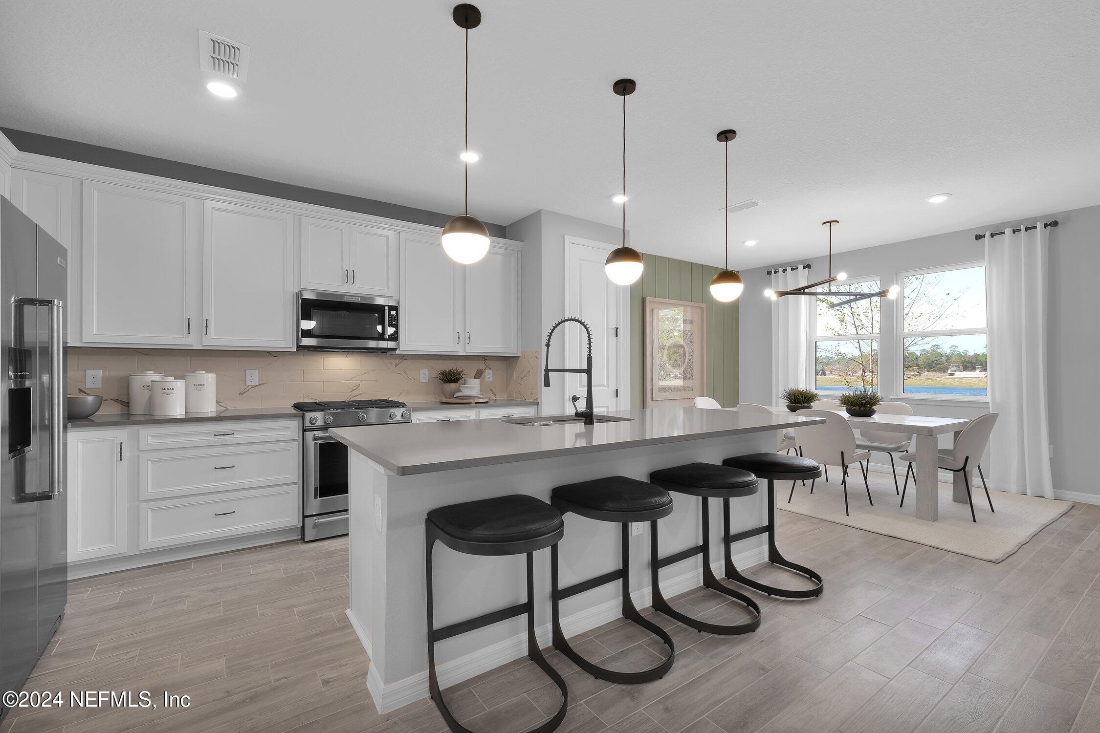 a kitchen with kitchen island granite countertop a sink a stove a dining table and chairs