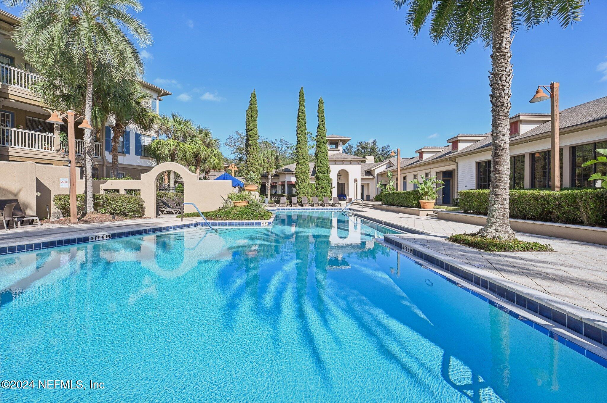 a view of a swimming pool with a lawn chairs under an umbrella