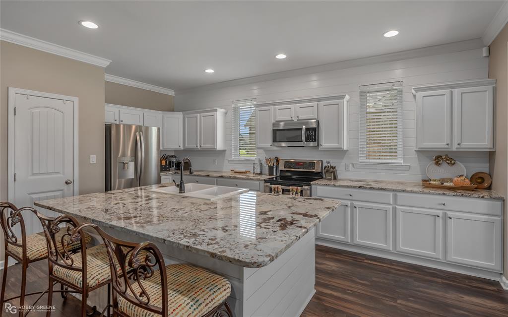 a kitchen with kitchen island granite countertop a stove sink microwave and refrigerator