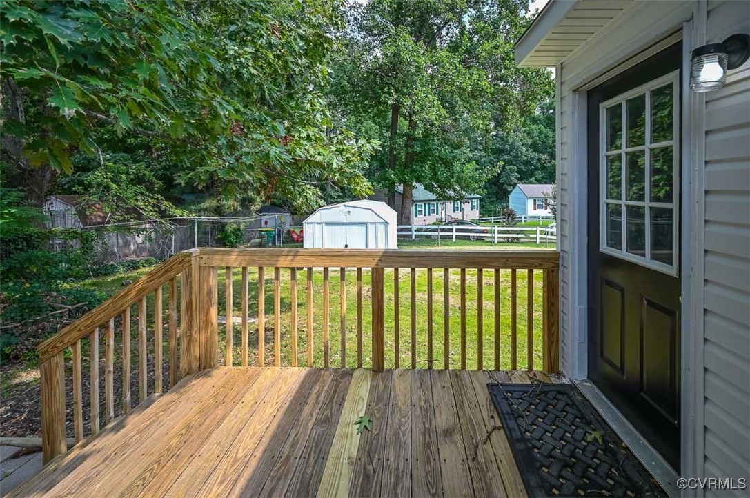 Wooden terrace featuring a yard and a shed