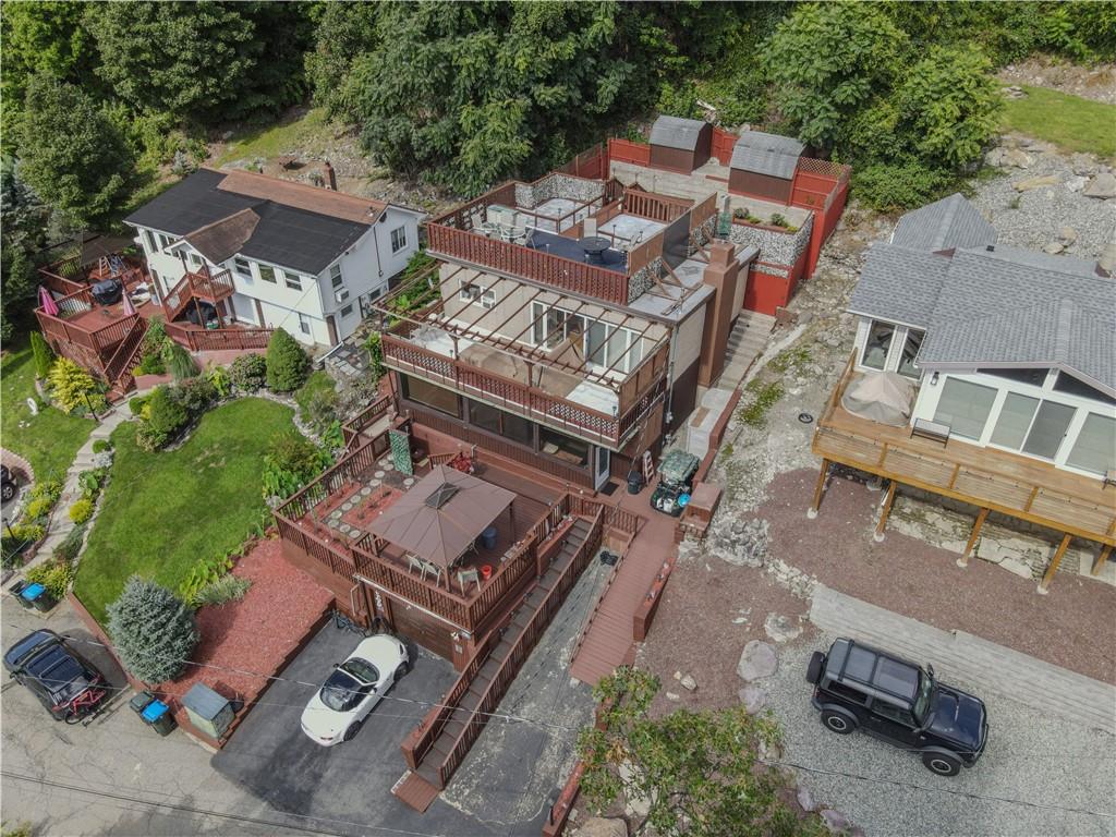 Bird's eye view including home, garage, property, decks and fenced in backyard with sheds.