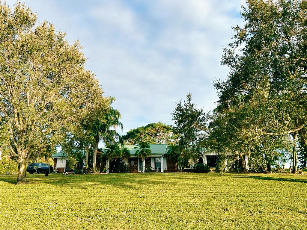 a view of a house with a big yard and large trees