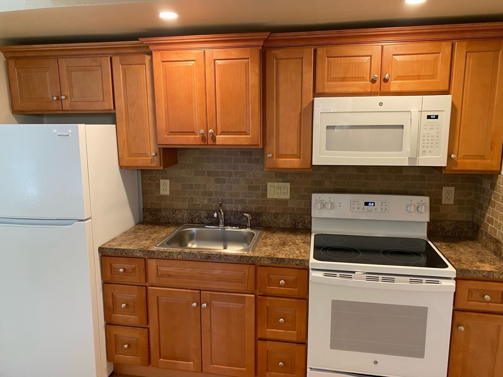 a kitchen with granite countertop a sink stove and refrigerator