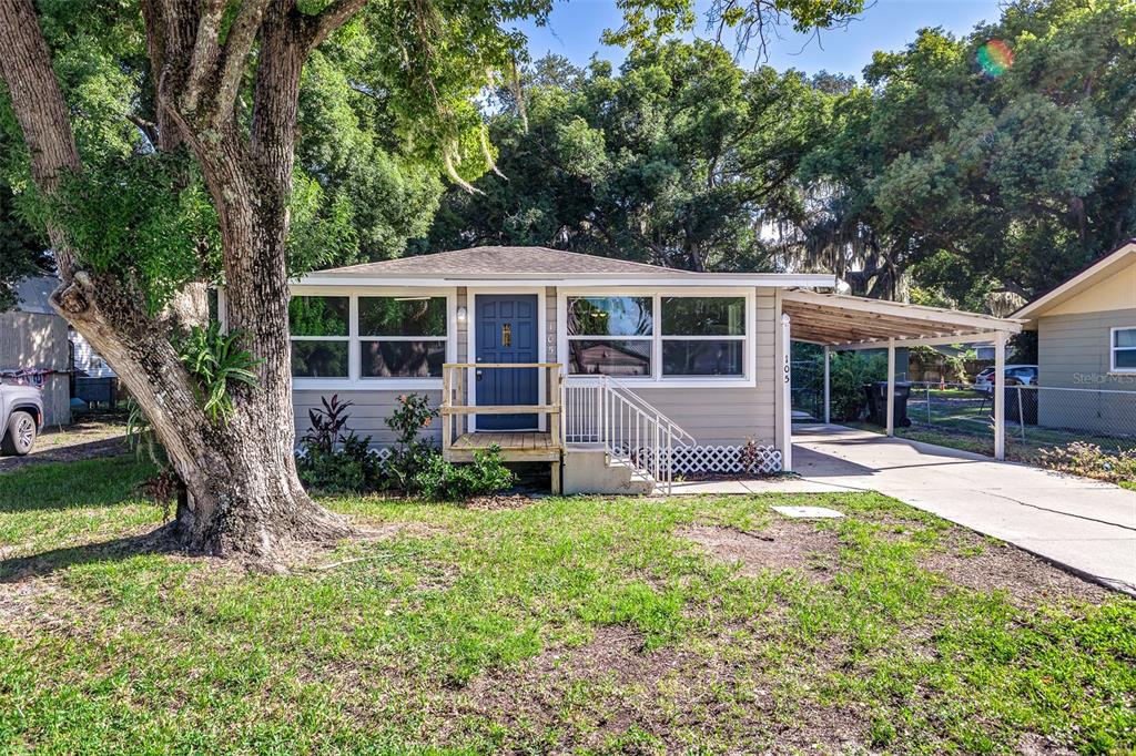 a view of a house with a yard and large tree