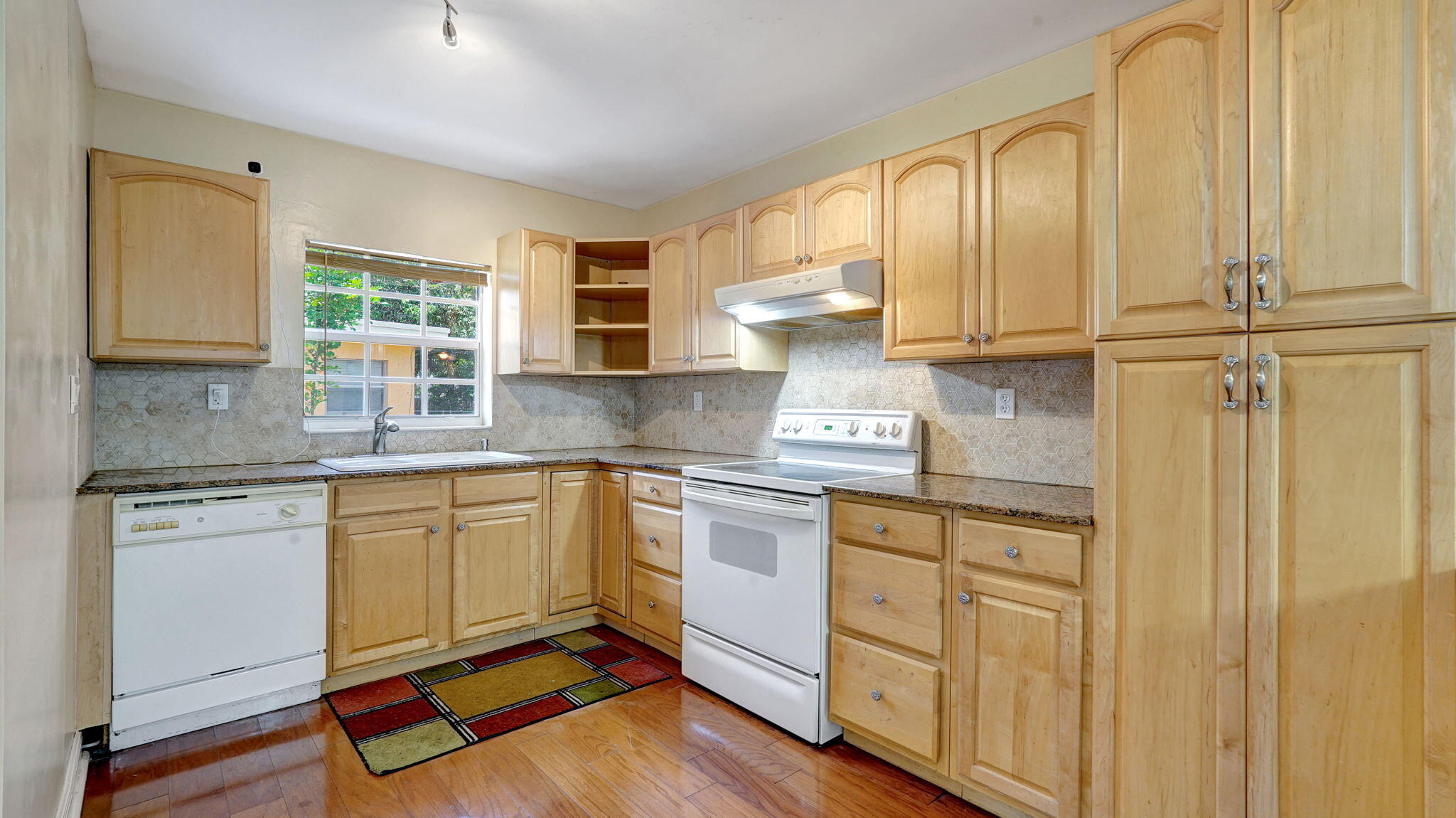 a kitchen with stainless steel appliances granite countertop a stove a sink and white cabinets with wooden floor