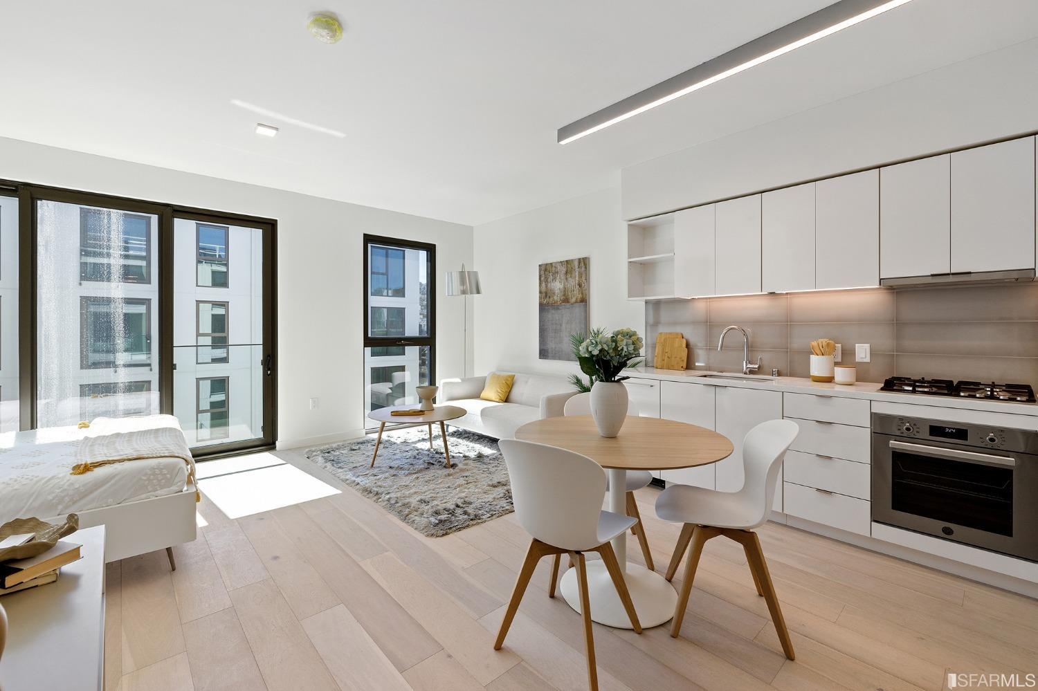 a kitchen with stainless steel appliances a dining table chairs and a refrigerator