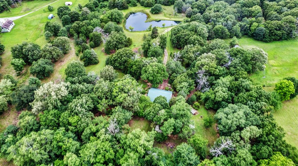 an aerial view of residential house with outdoor space and trees all around