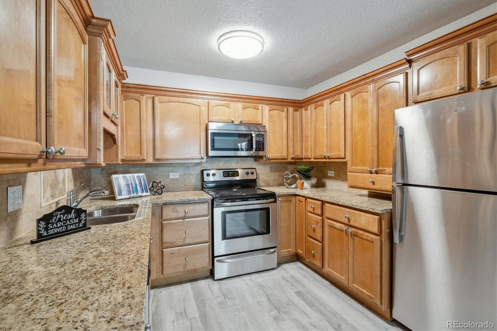 a kitchen with a refrigerator a stove top oven a sink and cabinets