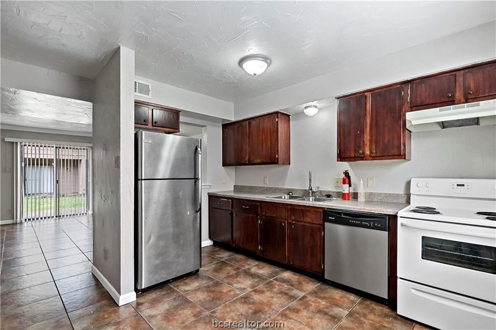 a kitchen with a refrigerator sink and wooden cabinets