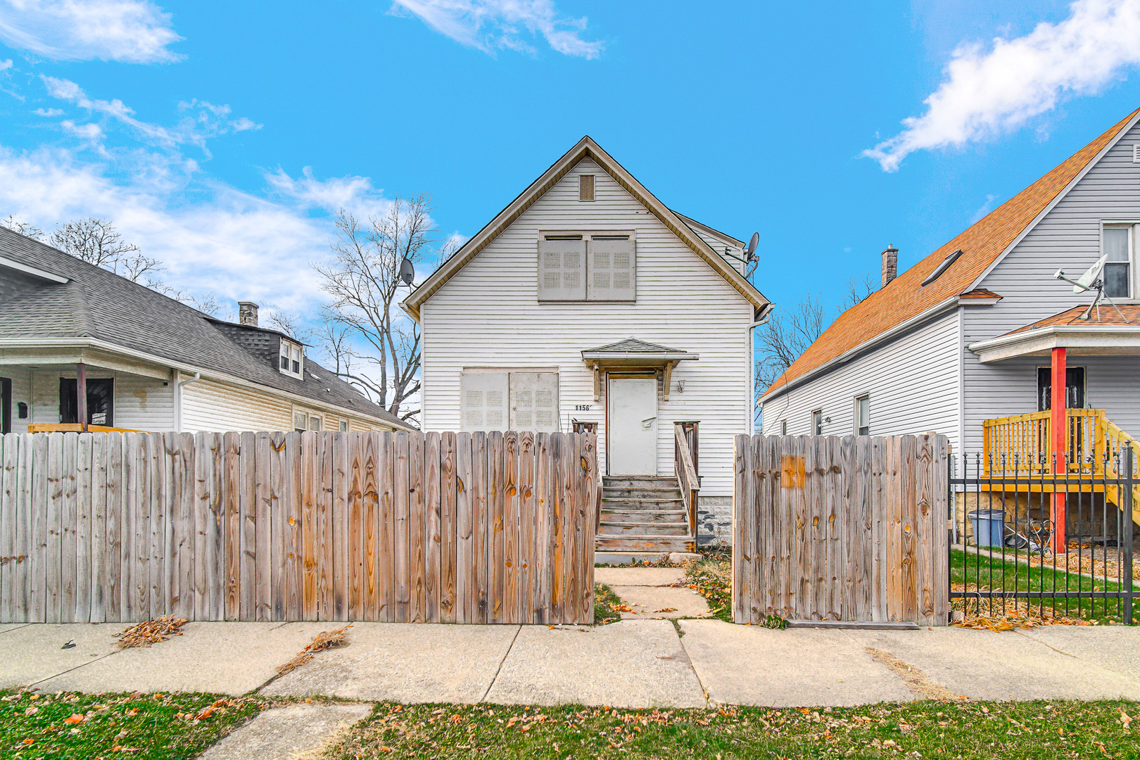 a view of a small house with wooden fence