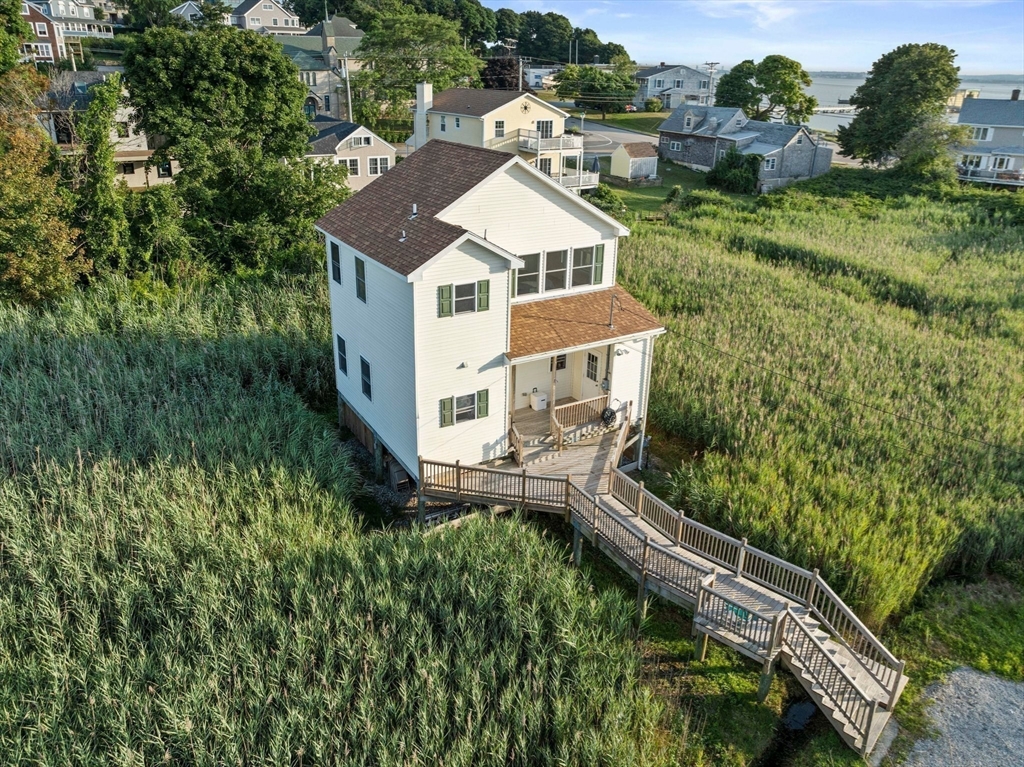 a aerial view of a house with yard and trees in the background