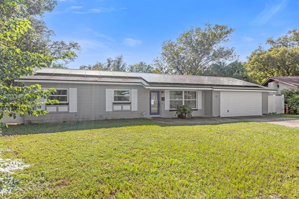 a front view of house with yard and trees in the background