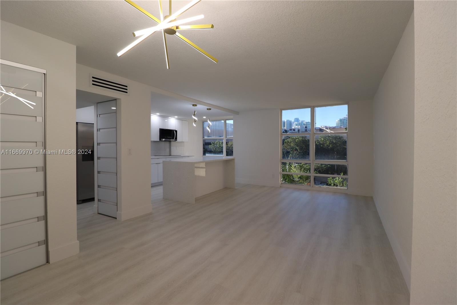 an empty room with kitchen and windows