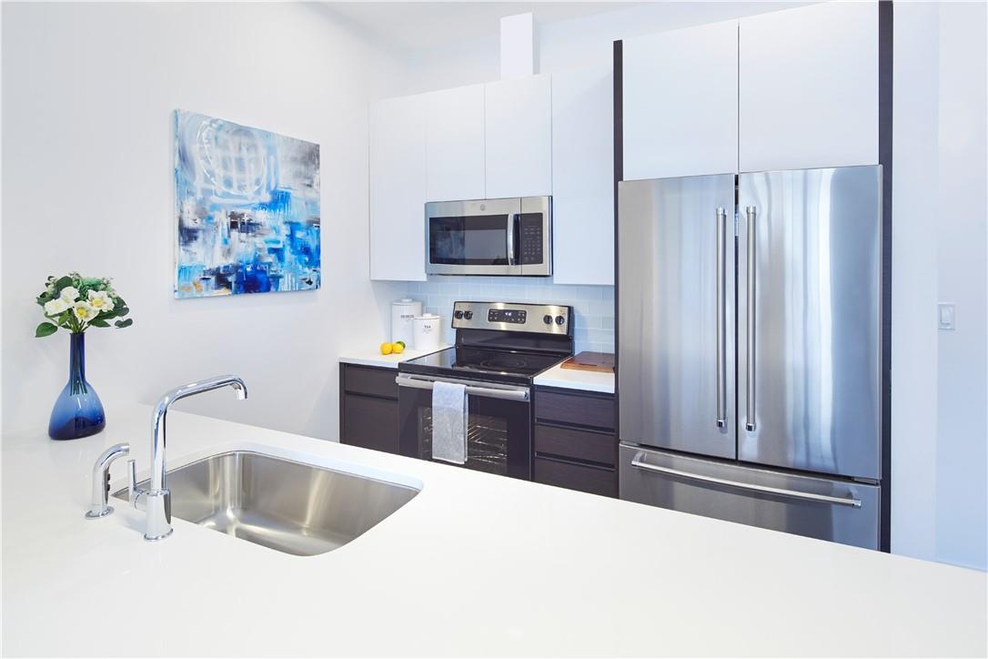 Kitchen with white cabinets, appliances with stainless steel finishes, sink, and tasteful backsplash