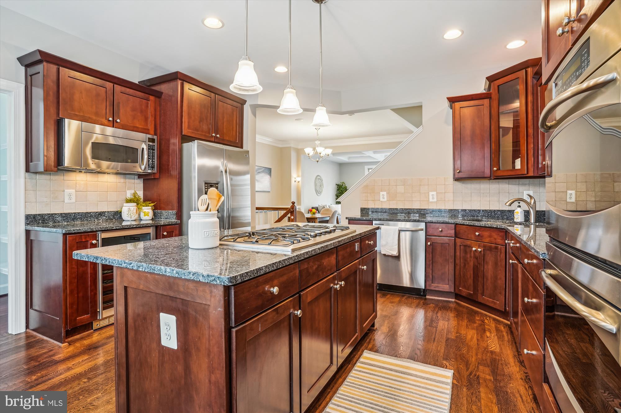 a kitchen with stainless steel appliances granite countertop a sink a stove and a wooden floors