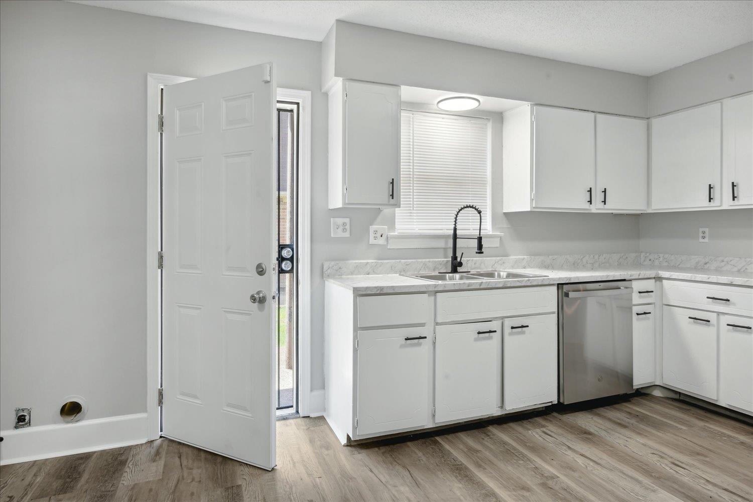 Kitchen featuring light hardwood / wood-style floors, white cabinetry, dishwasher, and sink