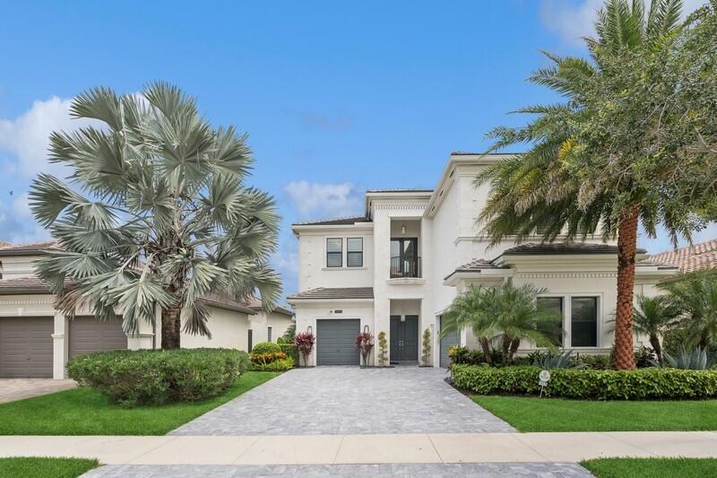 a front view of a white house with a yard and palm trees