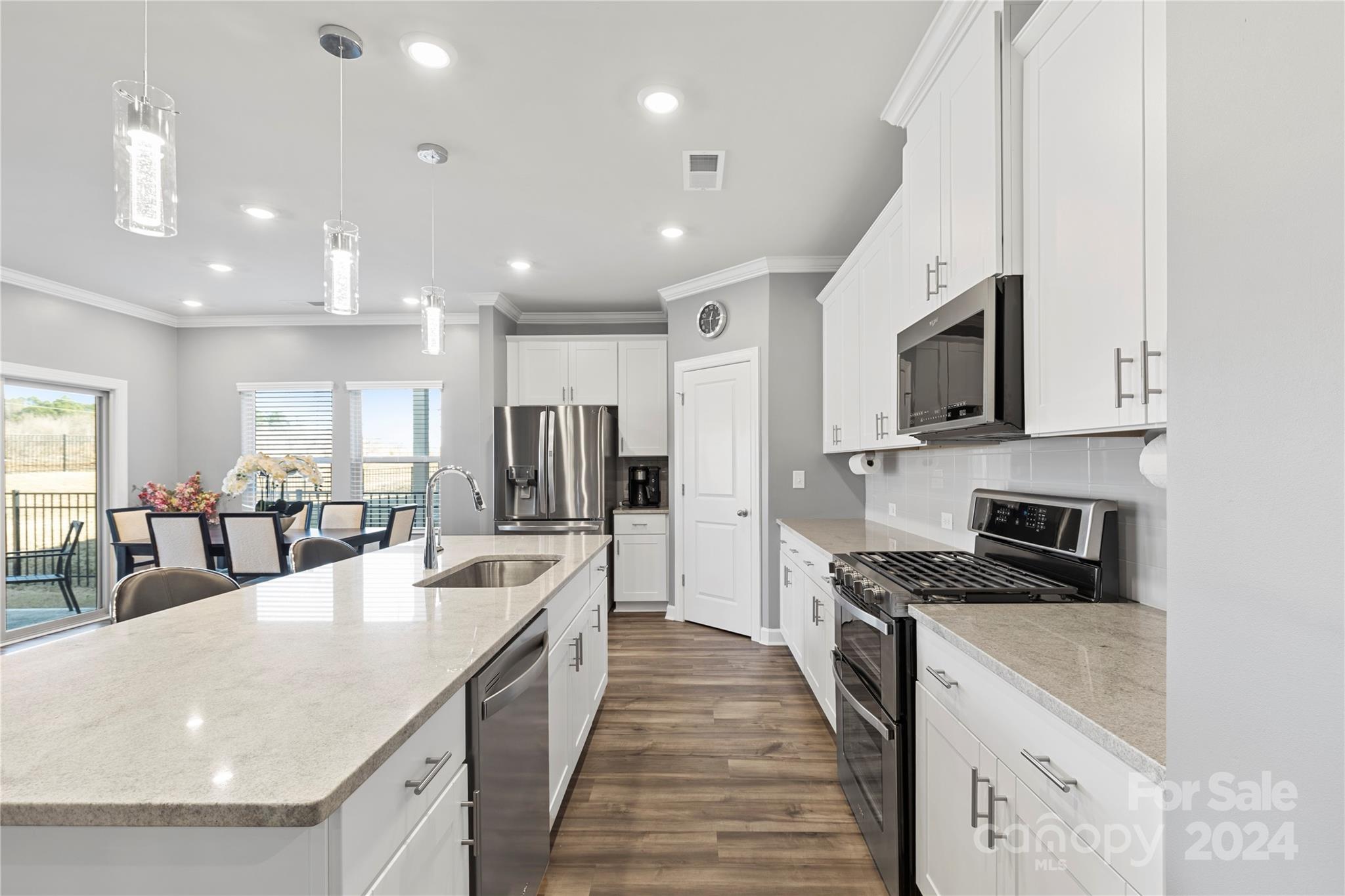 a large kitchen with kitchen island a large counter top space a sink stainless steel appliances and cabinets