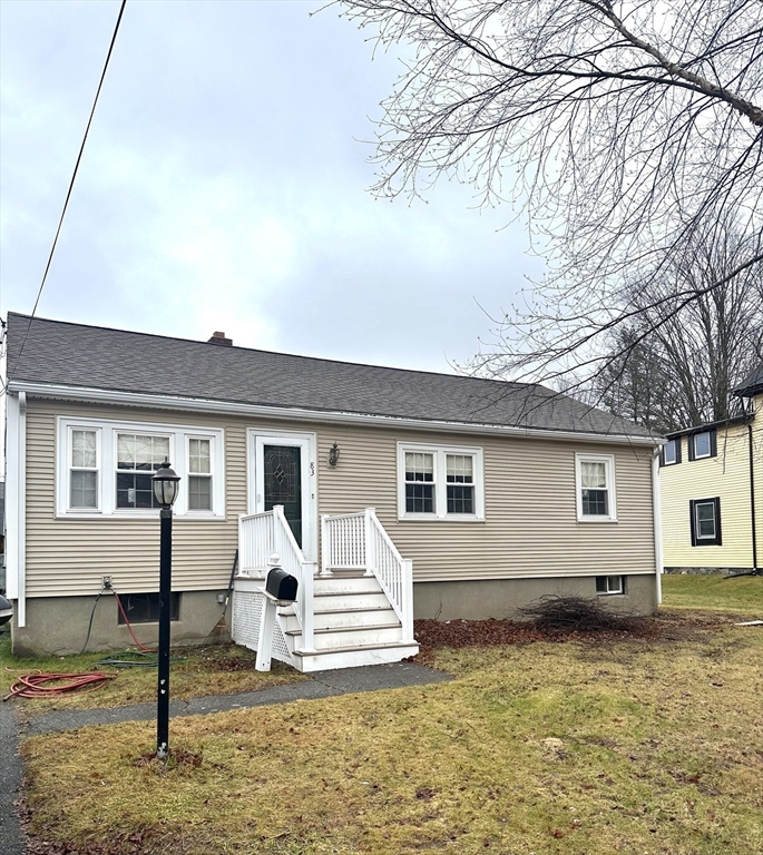 a view of a white house next to a yard with road