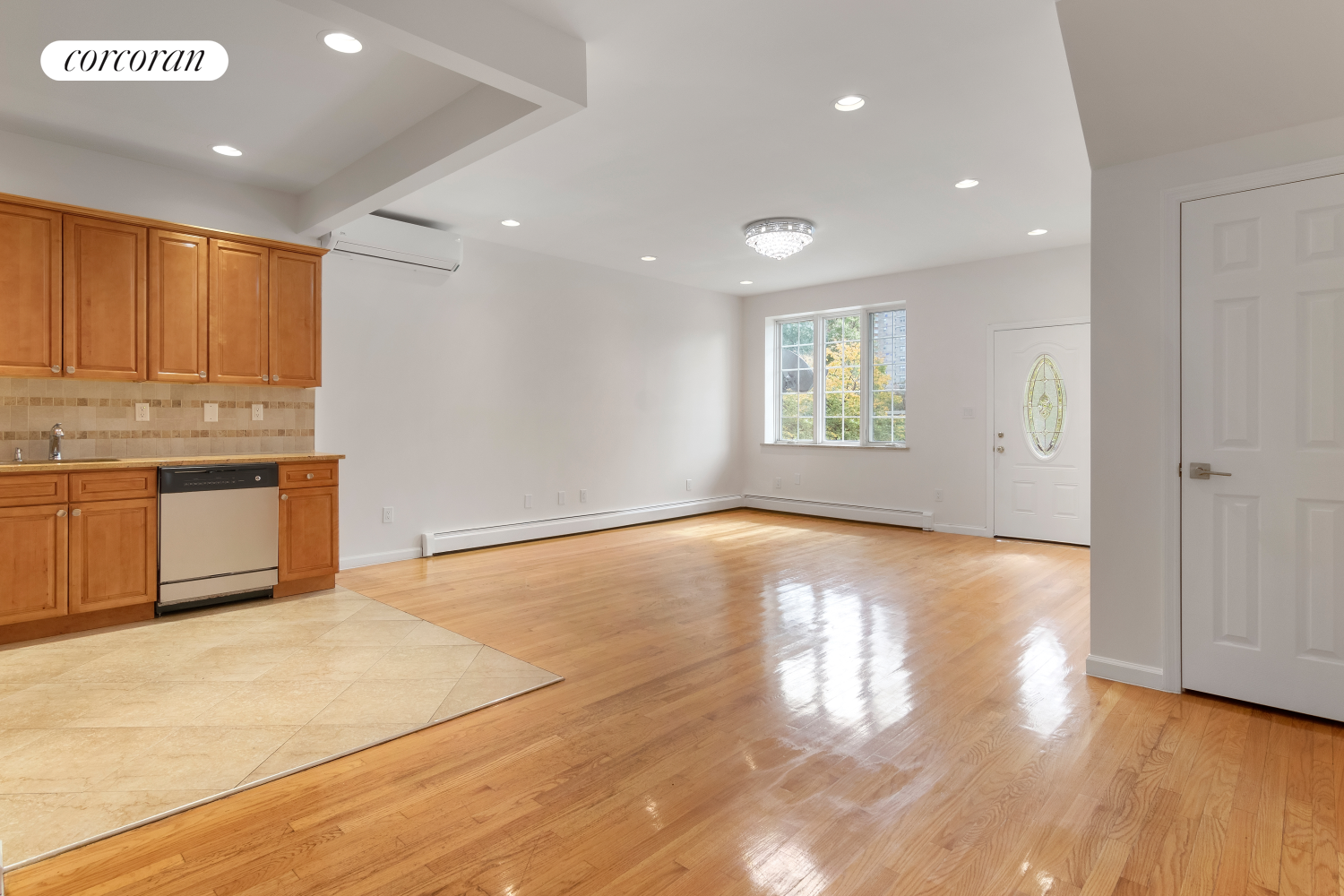 a view of an empty room with window and wooden floor