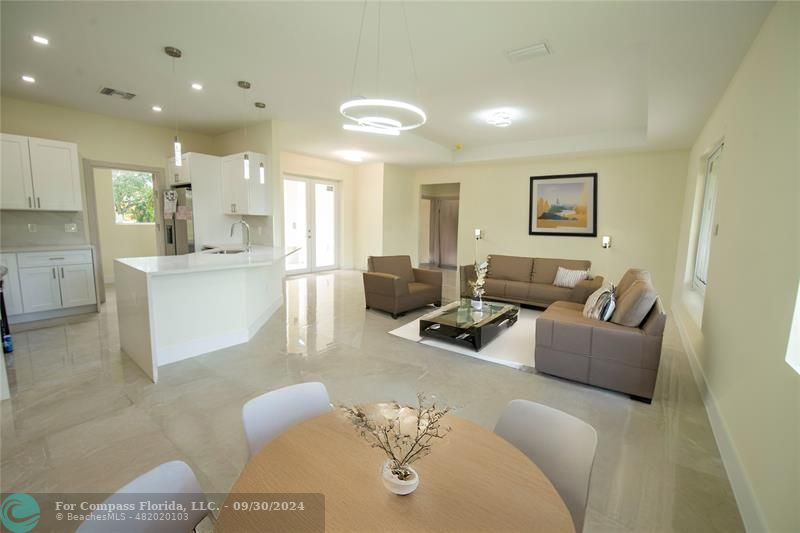 a living room with furniture and a dining table with kitchen view