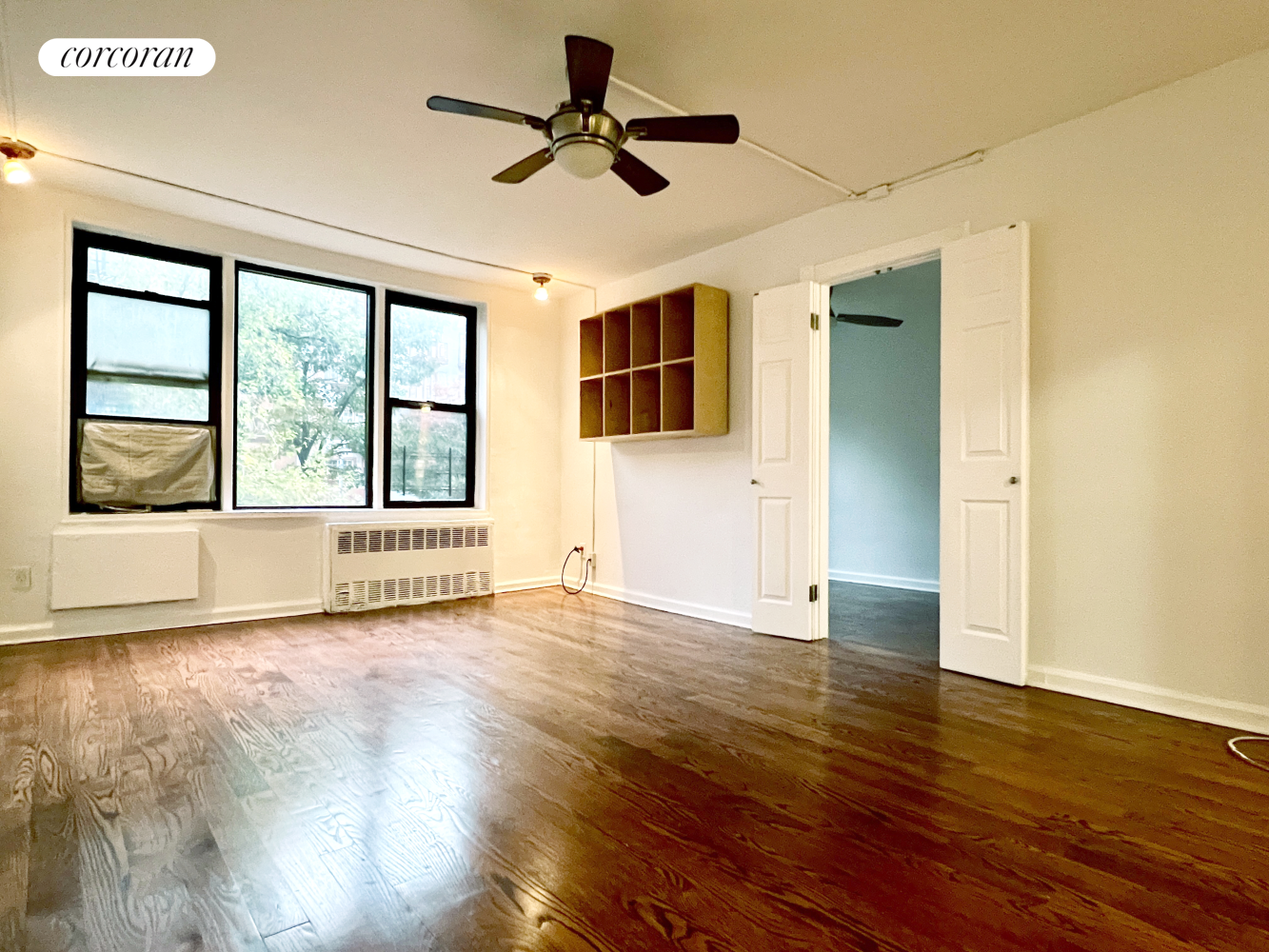 a view of an empty room with a window and wooden floor