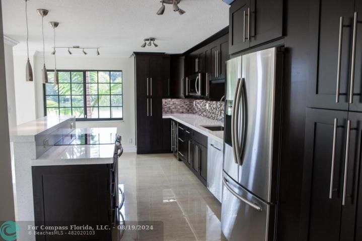 a kitchen with stainless steel appliances granite countertop a refrigerator a stove and a sink