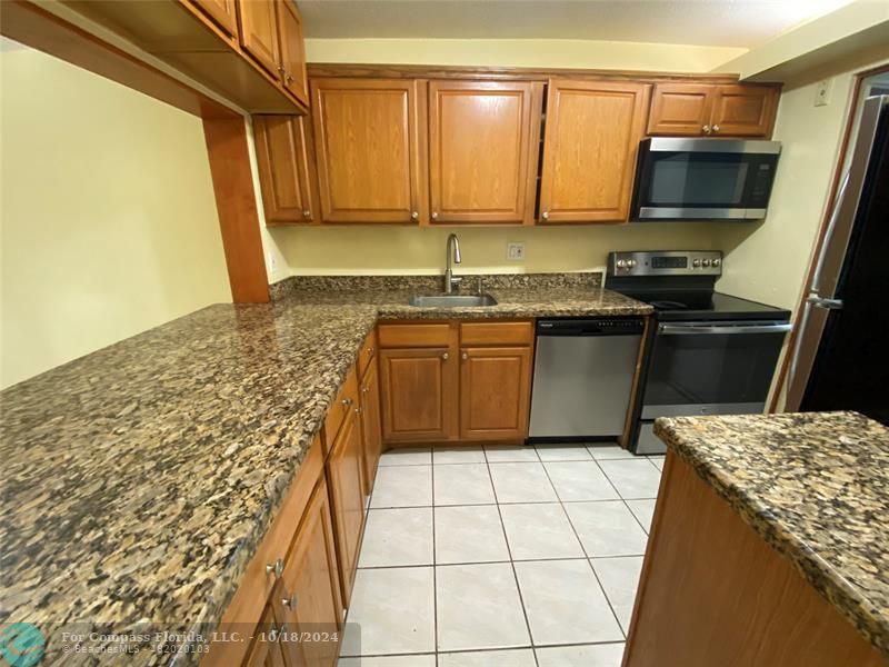 a kitchen with stainless steel appliances granite countertop a stove a sink and a microwave