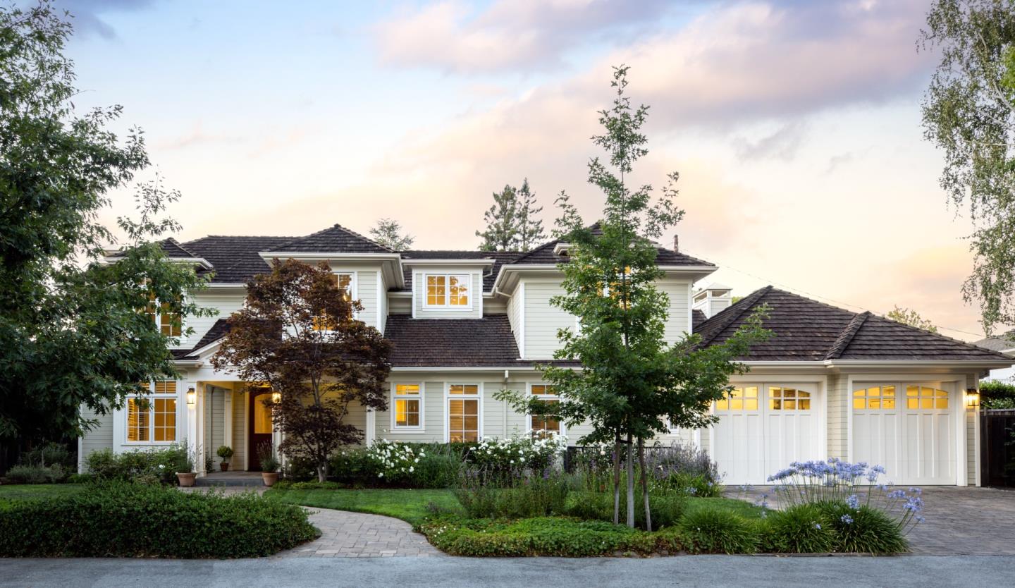 a front view of a house with a garden and a tree