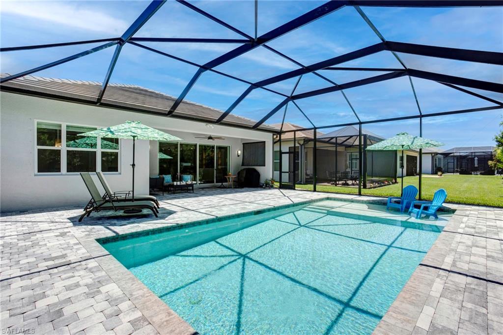 View of swimming pool featuring a yard, ceiling fan, glass enclosure, and a patio area