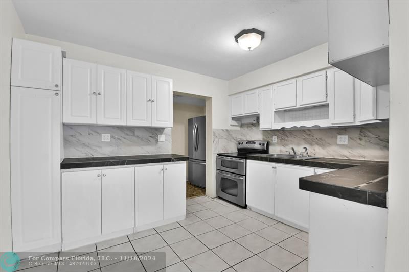 a kitchen with granite countertop white cabinets stainless steel appliances and a sink