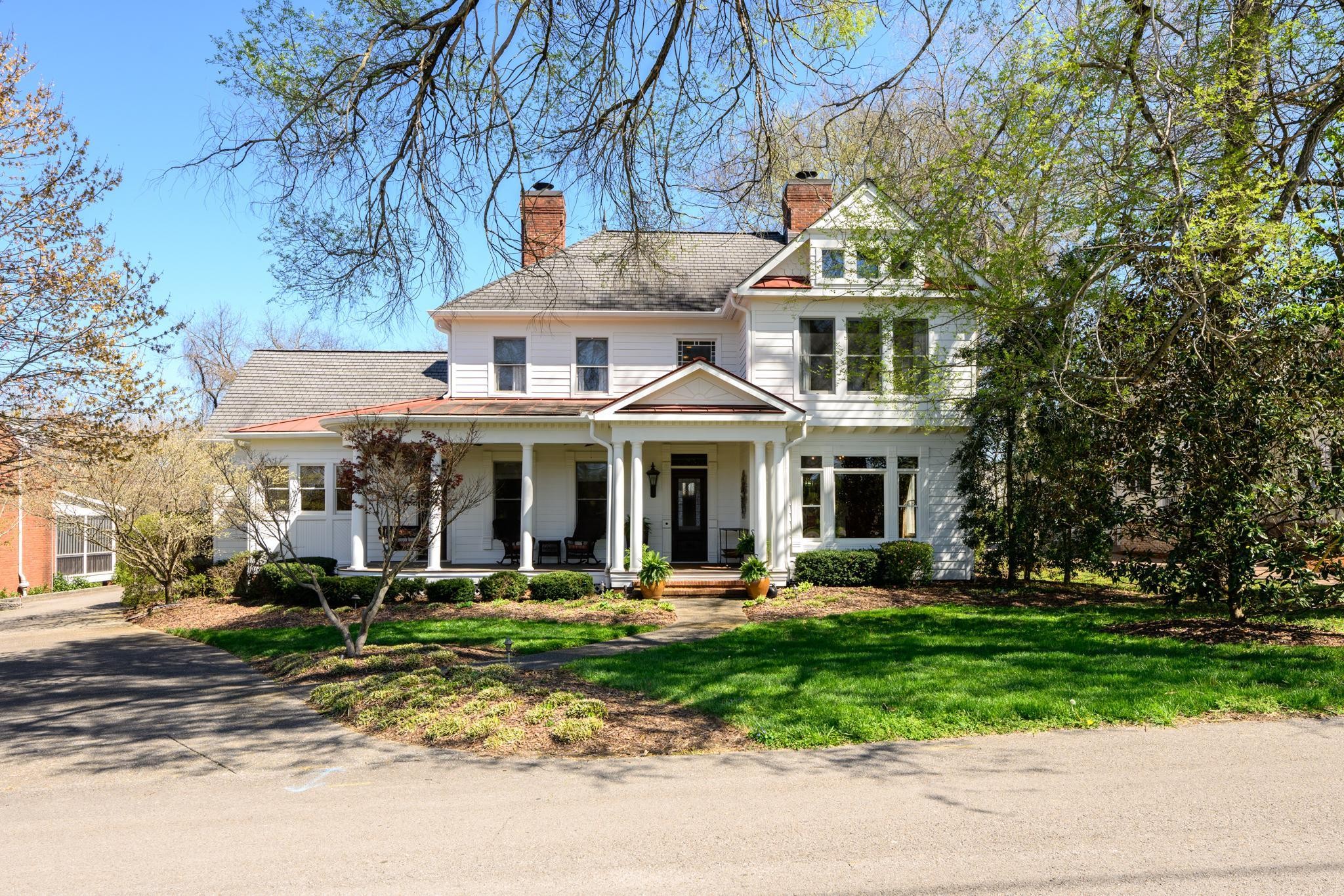 a front view of a house with garden and trees