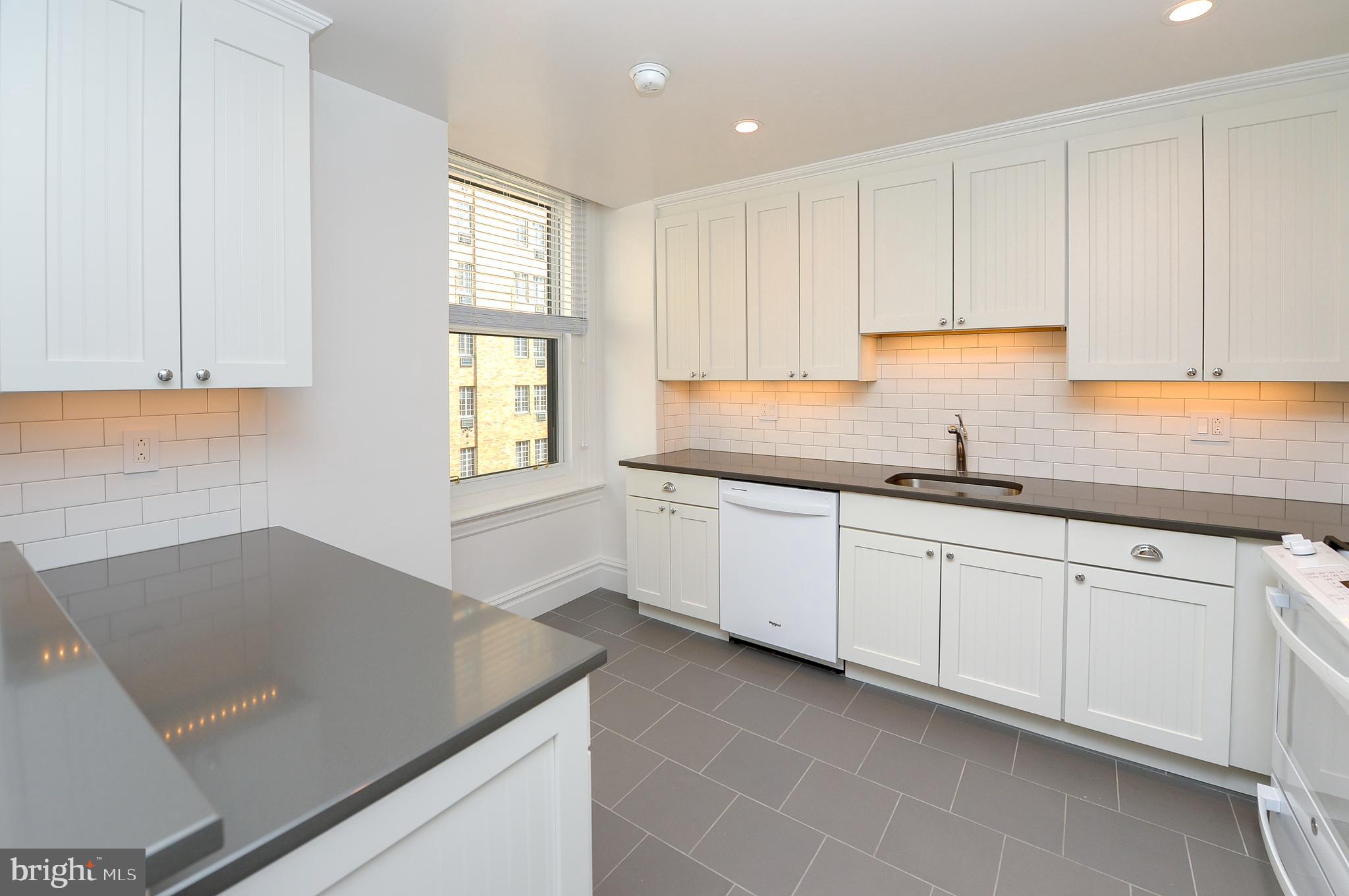 a kitchen with granite countertop white cabinets white appliances a sink and a window