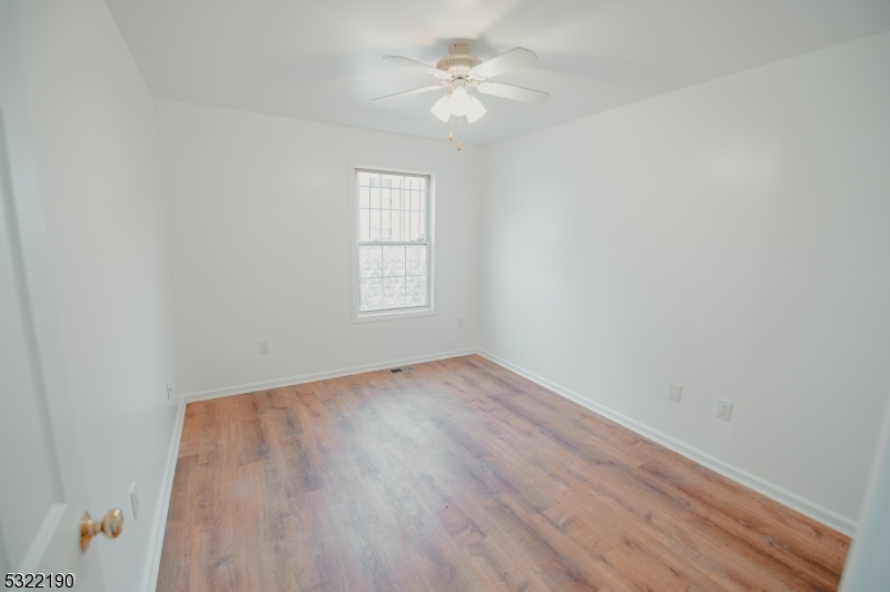 an empty room with a window and a ceiling fan