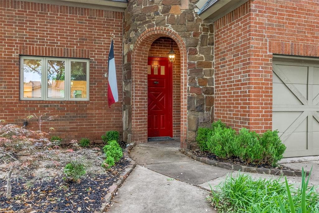 a view of a brick house with plants and large tree