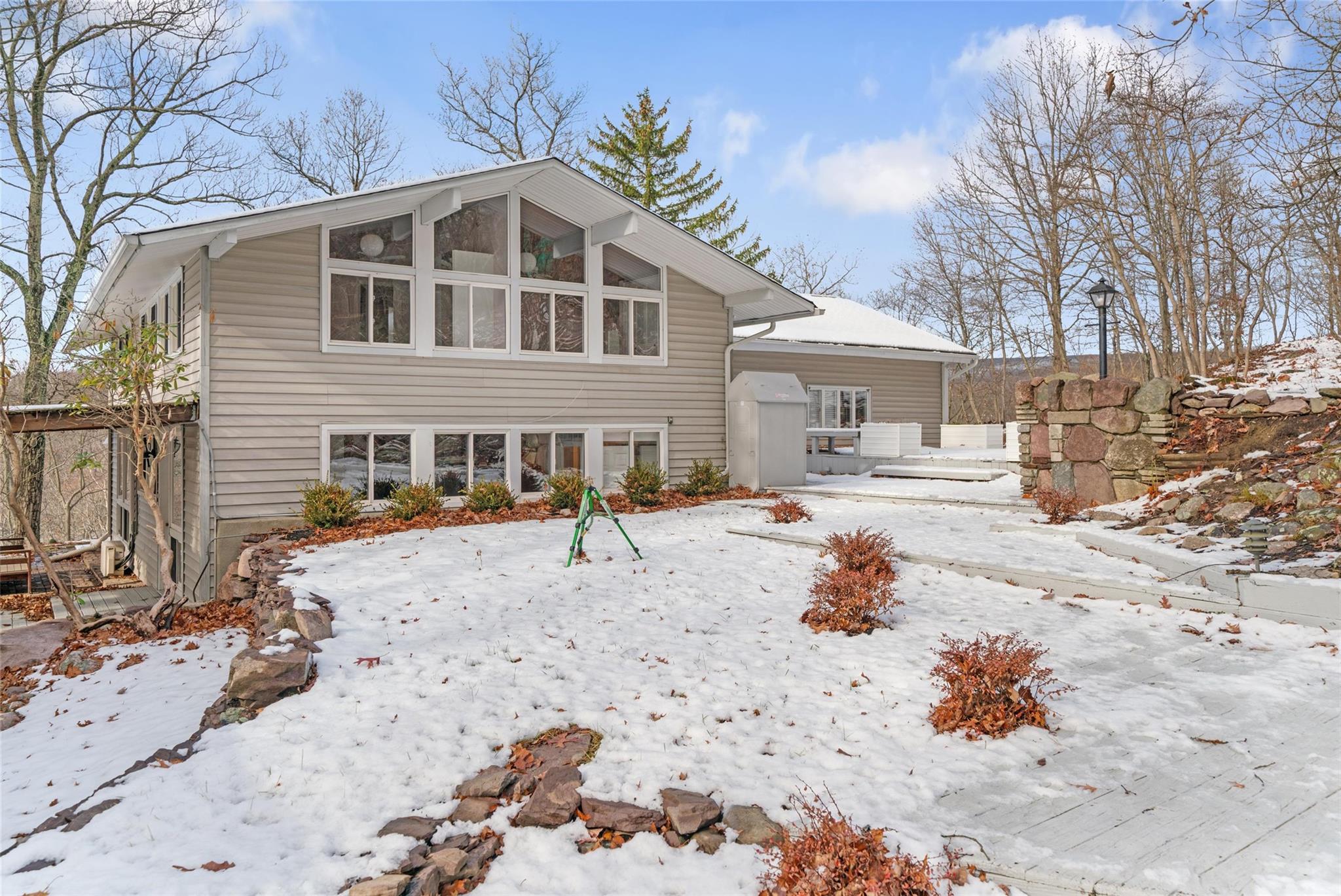 a front view of a house with a yard covered with snow and trees