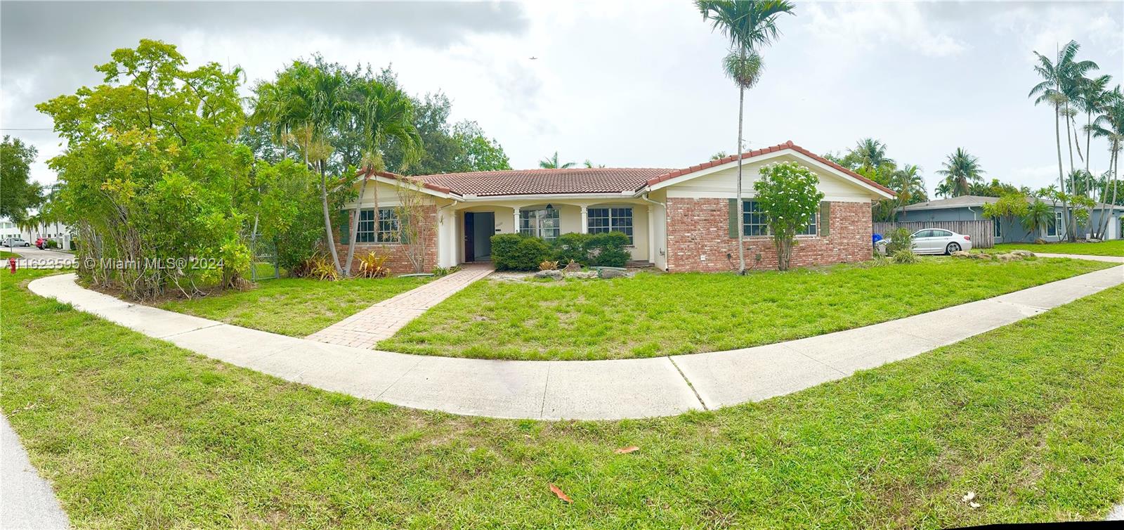 a view of a house with a big yard potted plants and palm trees