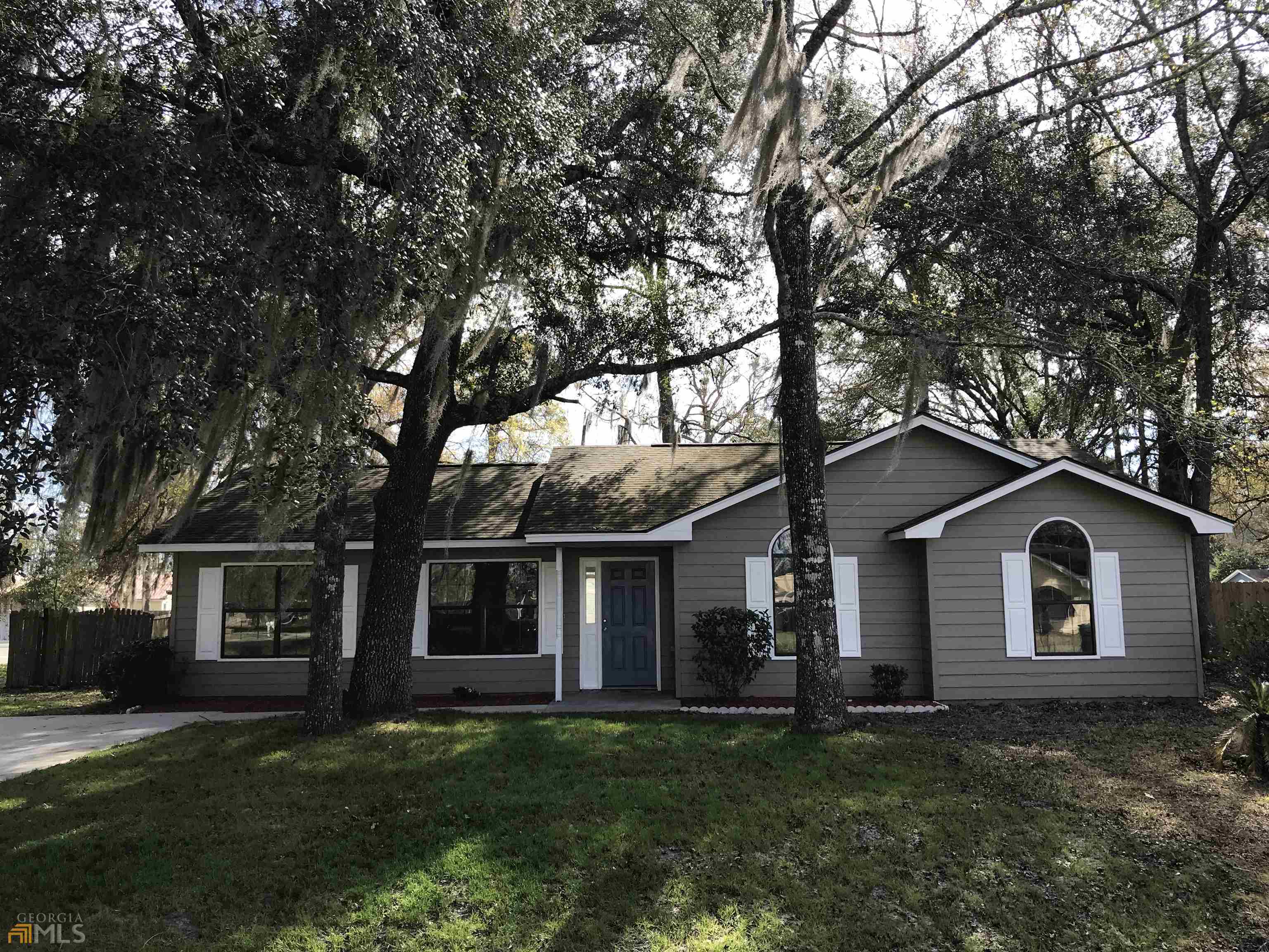 a view of a yard in front of a house with large trees