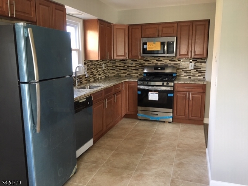 a kitchen with granite countertop a refrigerator stove and a sink