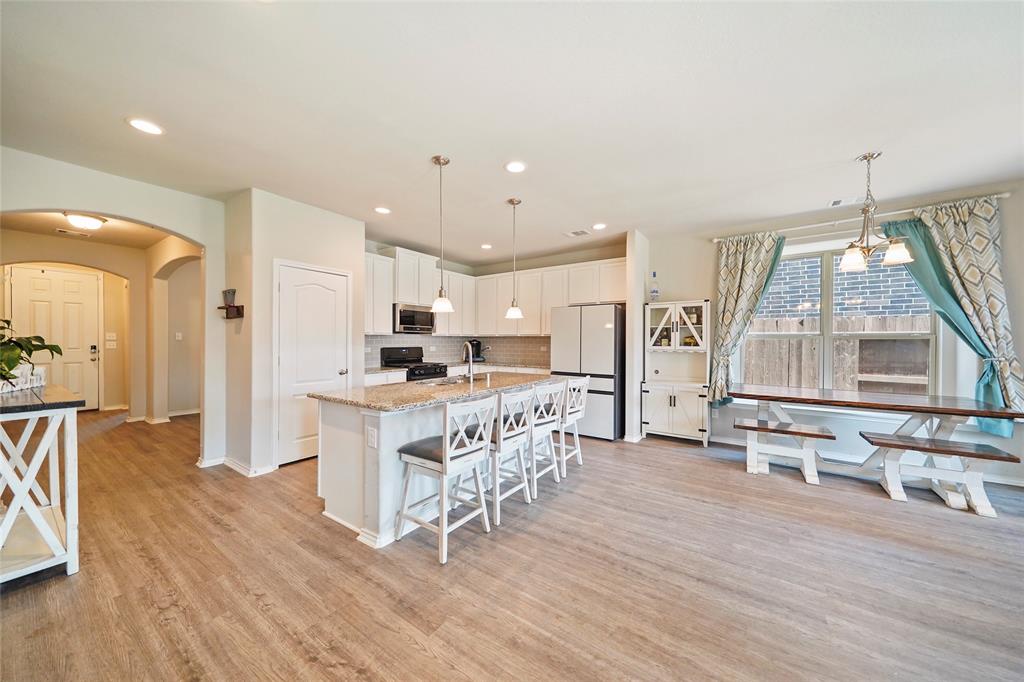 a kitchen with stainless steel appliances kitchen island wooden floors and white cabinets