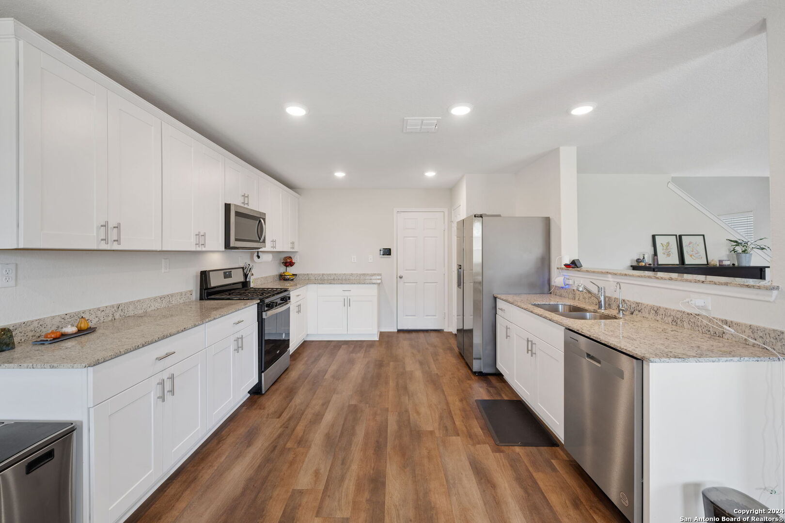 a large kitchen with stainless steel appliances lots of counter space and wooden floor