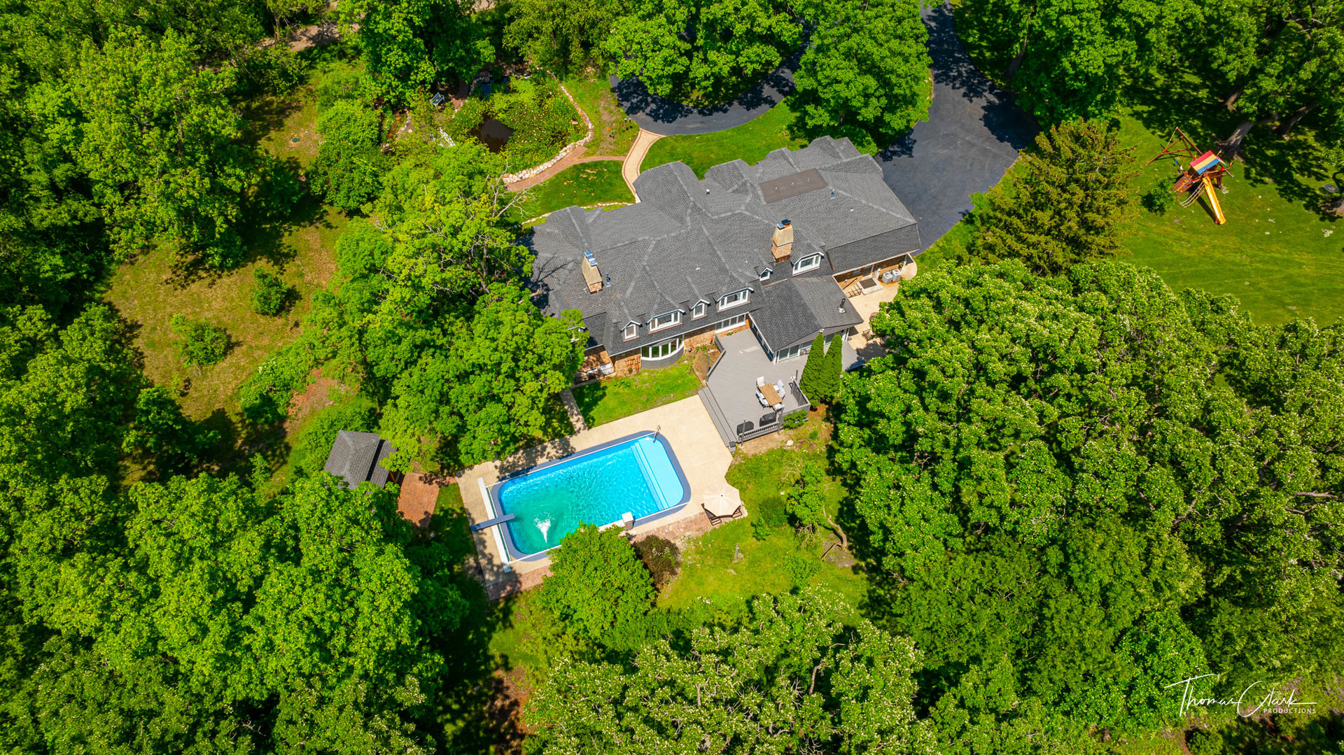 an aerial view of residential house with outdoor space and trees all around