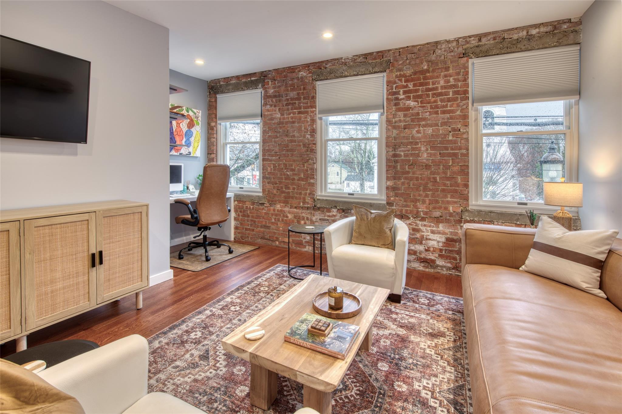 Living room featuring dark hardwood / wood-style flooring and brick wall