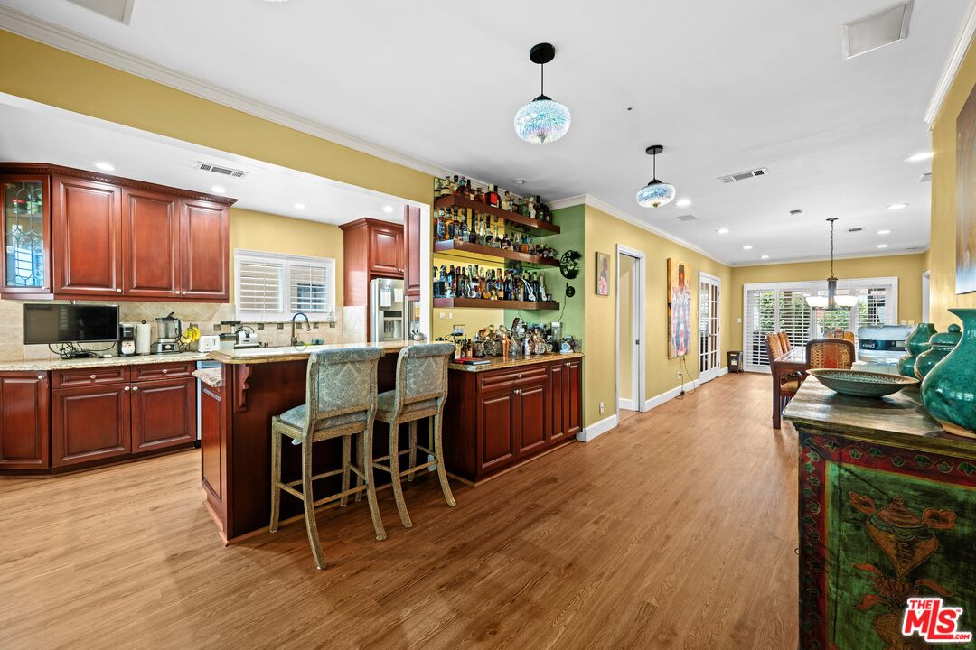 a kitchen with stainless steel appliances kitchen island granite countertop a table chairs and a refrigerator