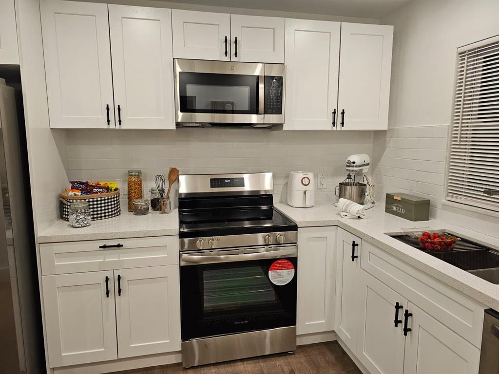 a kitchen with stainless steel appliances granite countertop white cabinets and a stove