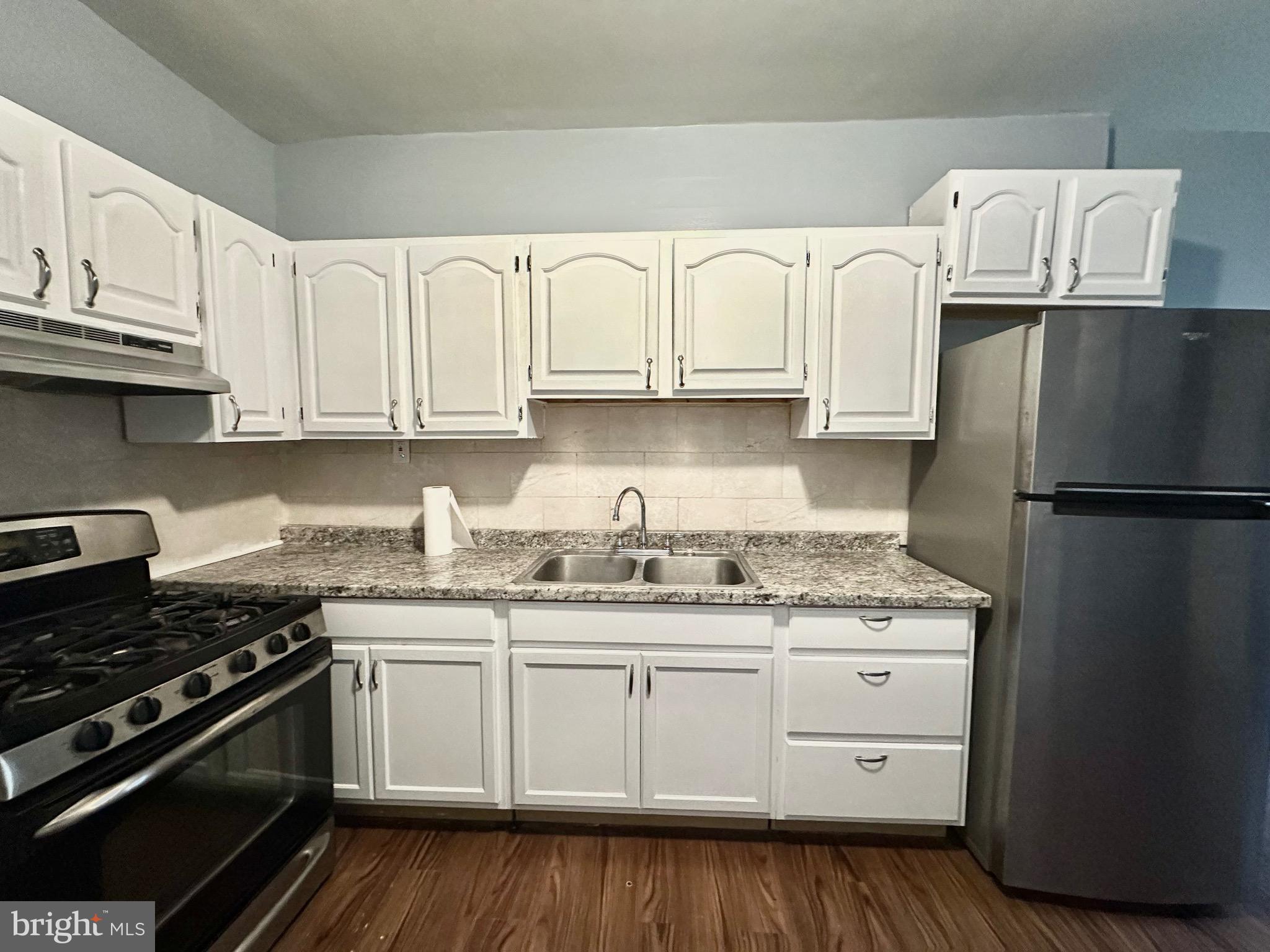 a kitchen with granite countertop a sink stove and refrigerator