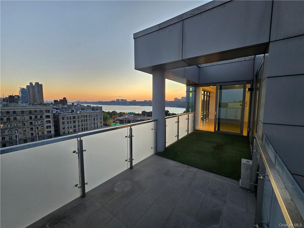 Patio terrace at dusk featuring a water view and a balcony